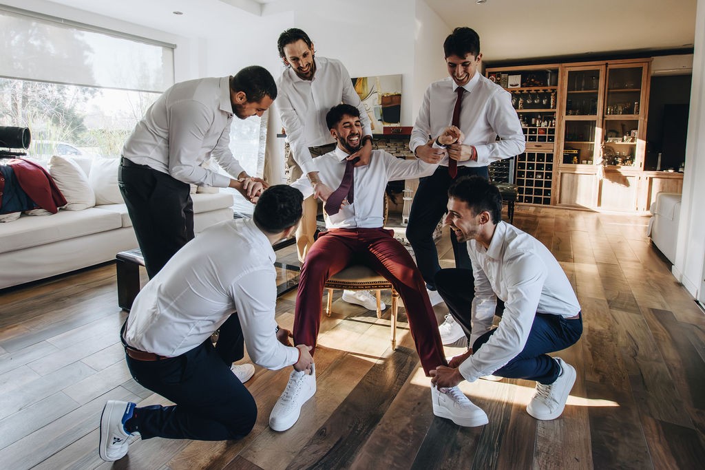 Los padrinos ayudándose con los zapatos