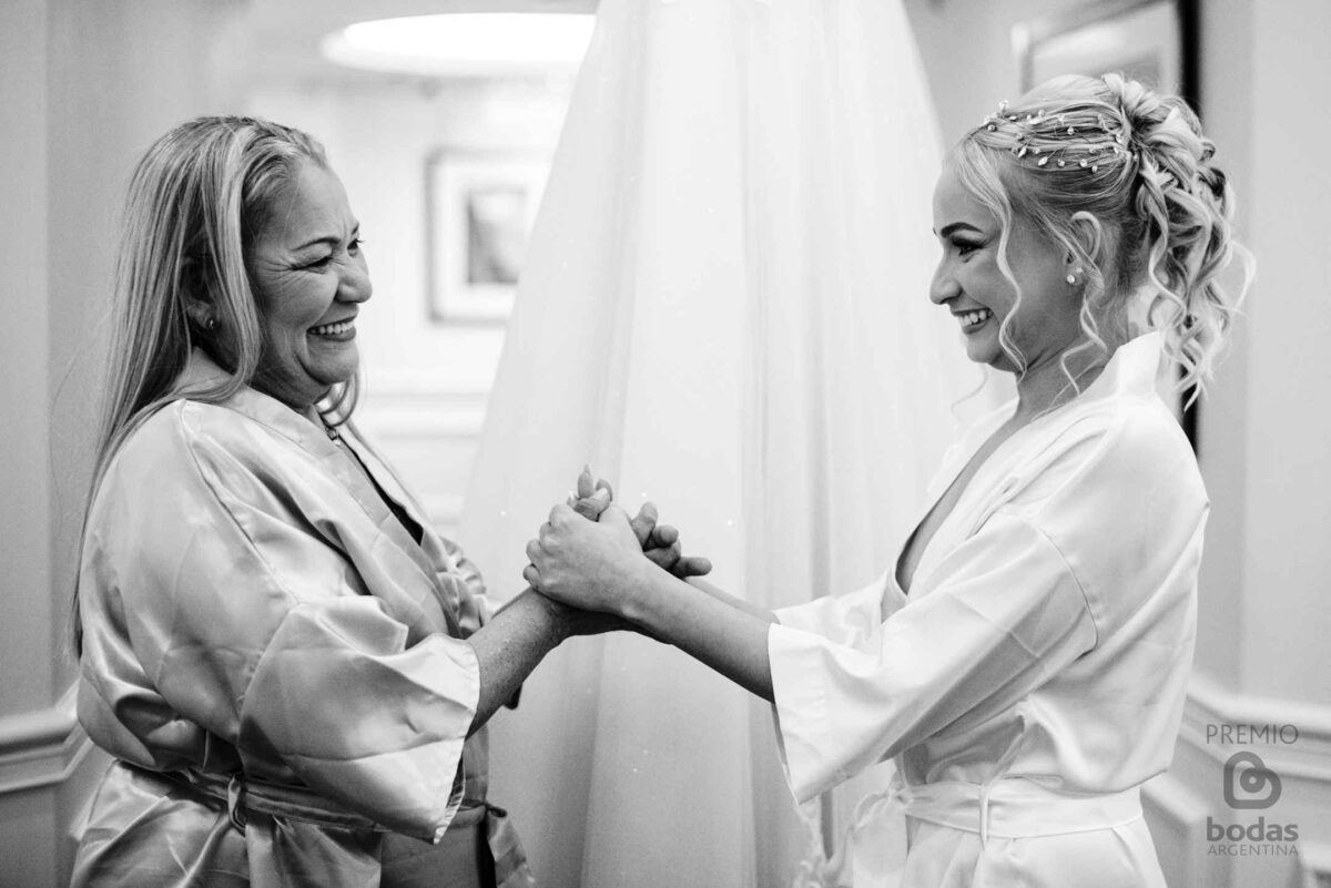 Novia y su mamá tomadas de las manos en el getting ready