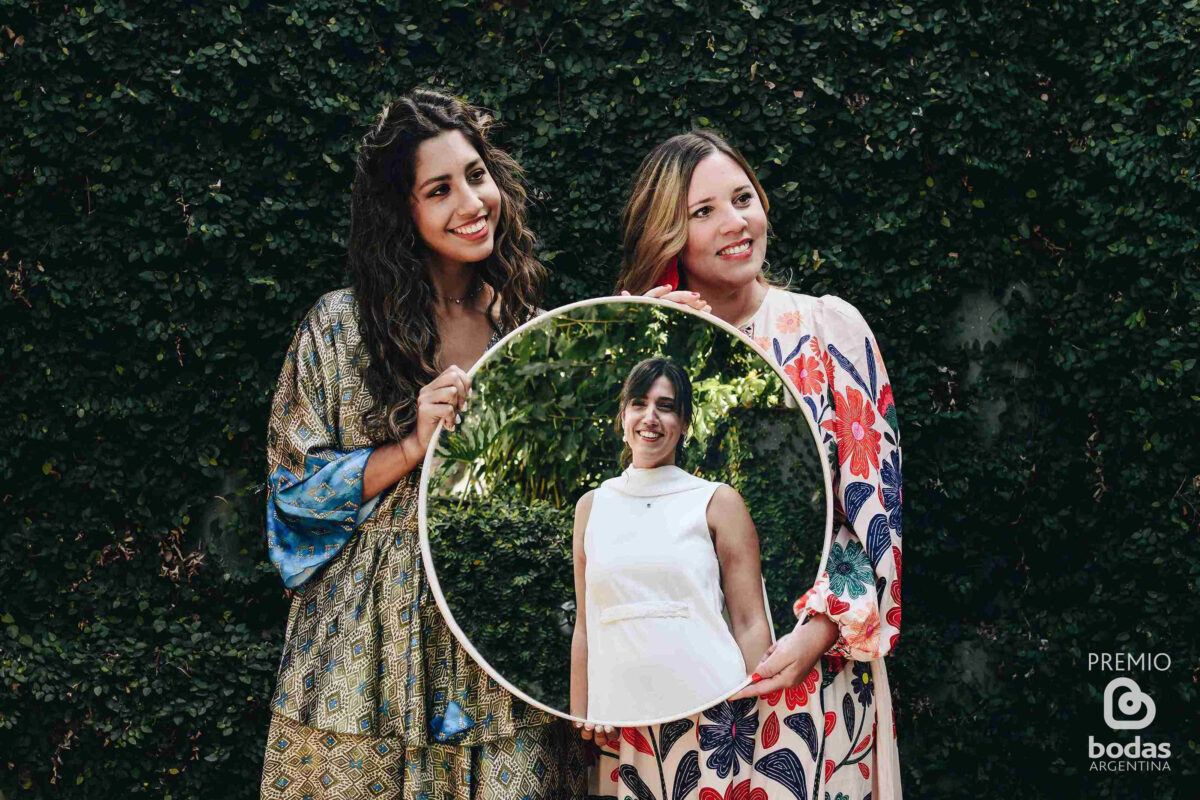 Amigas sosteniendo un marco circular en el jardín