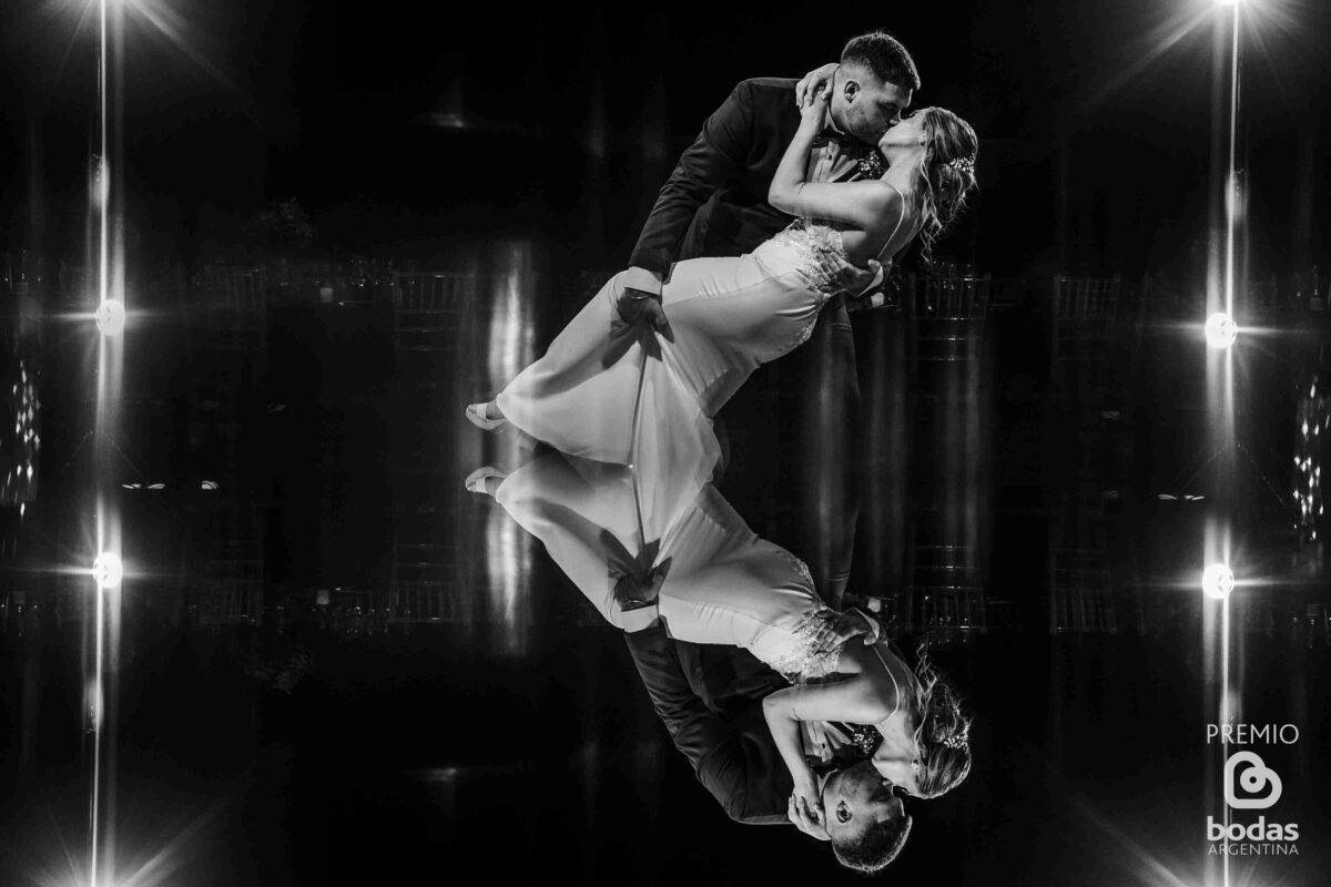 Novios besándose con reflejo en el piso durante la fiesta